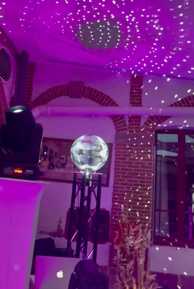 Boule à facettes géante illuminée sur son pied, reflets sur les murs de briques