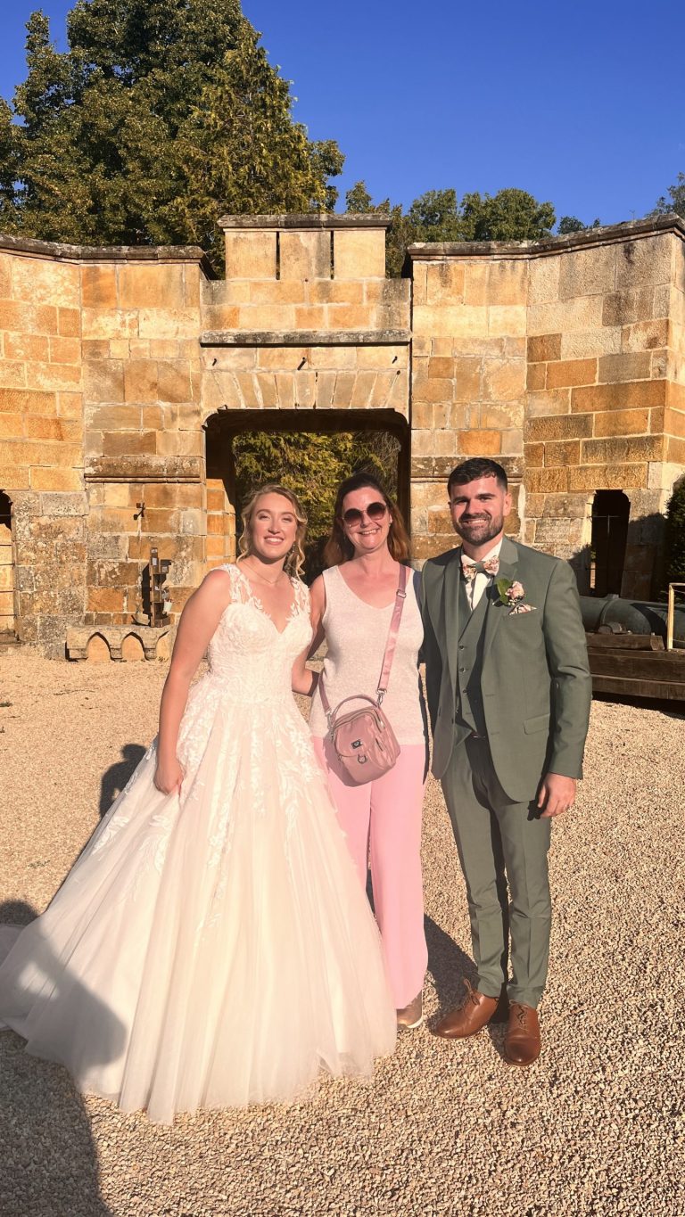 Stéphanie, DJ Stephevent63, avec les mariés Emma et Lucas devant la porte fortifiée du Château de la Grange Fort
