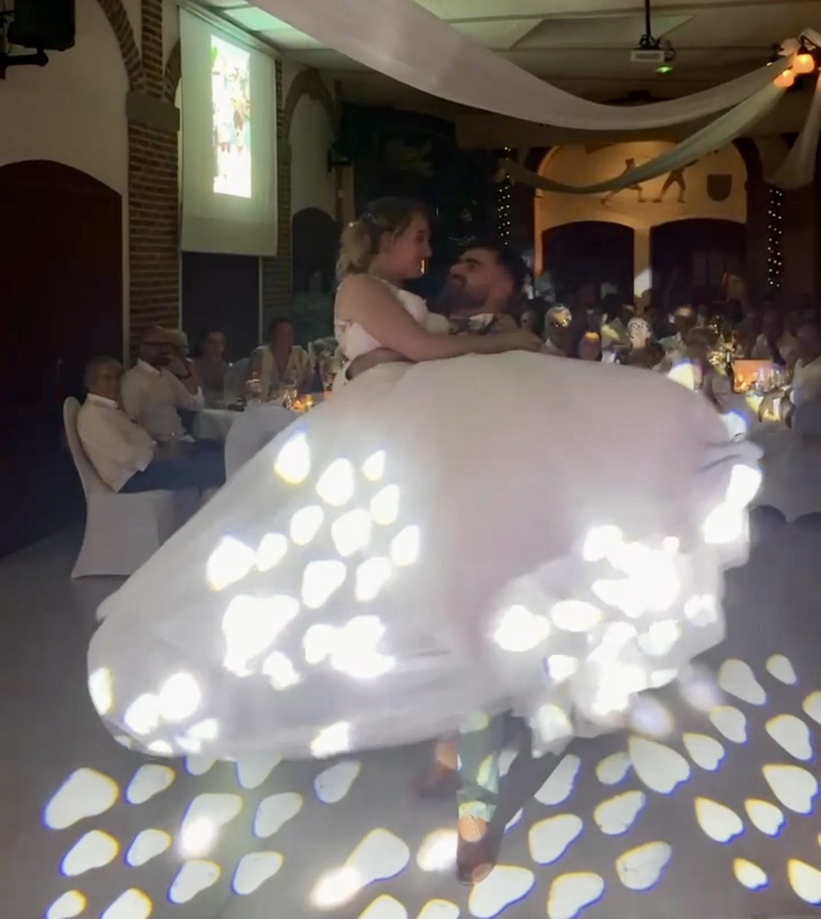 Ouverture de bal chorégraphiée d'Emma et Lucas, la robe de la mariée virevolte sous les jeux de lumière au Château de la Grange Fort