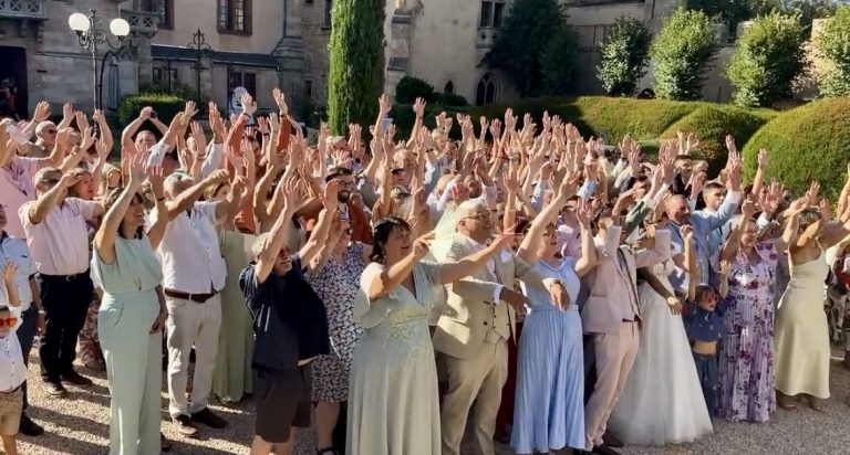 Les invités d'Héloïse et Arnaud lèvent les bras dans les jardins du Château de la Grange Fort
